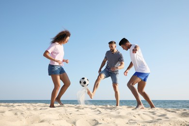 Group of friends playing football on beach