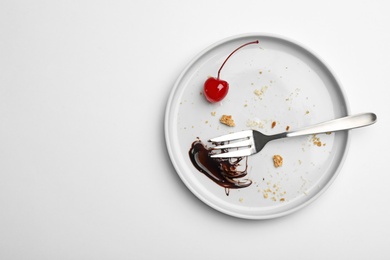 Photo of Dirty plate with food leftovers, fork and canned cherry on white background, top view