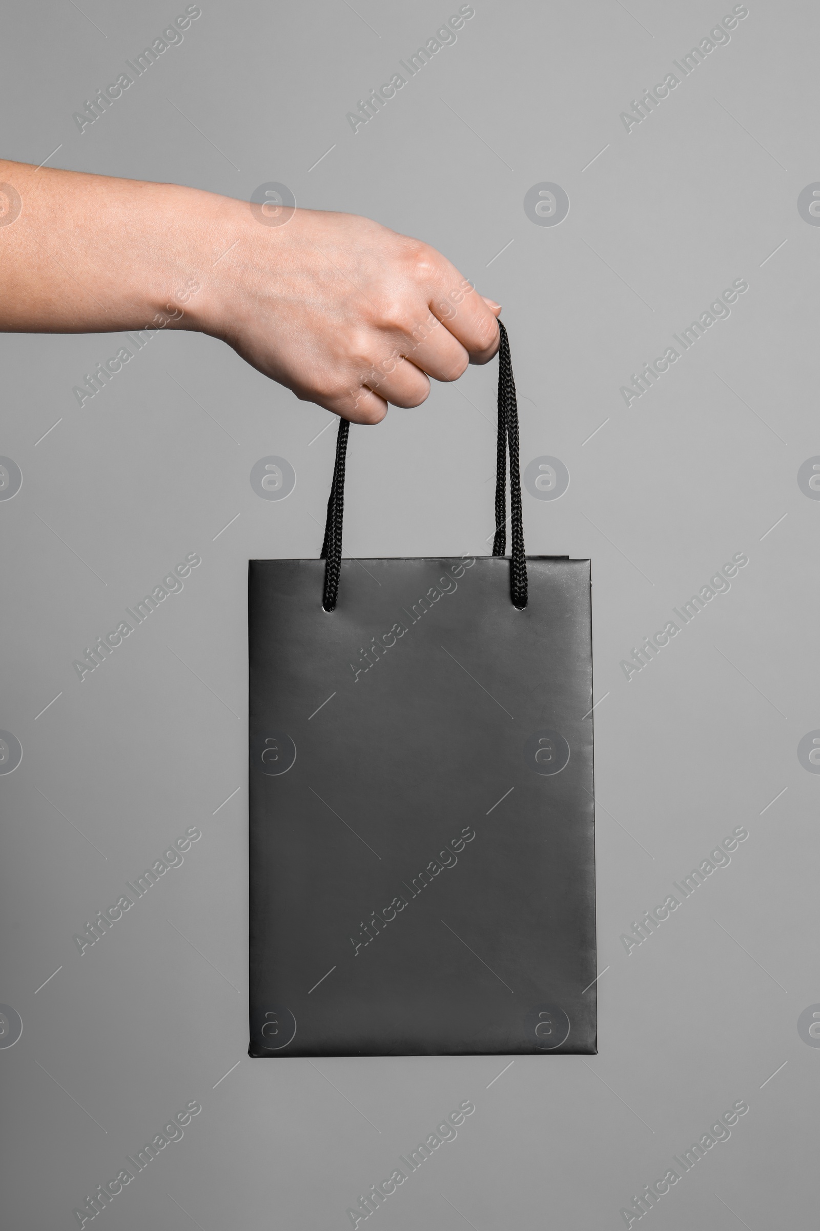 Photo of Woman holding paper shopping bag on grey background, closeup