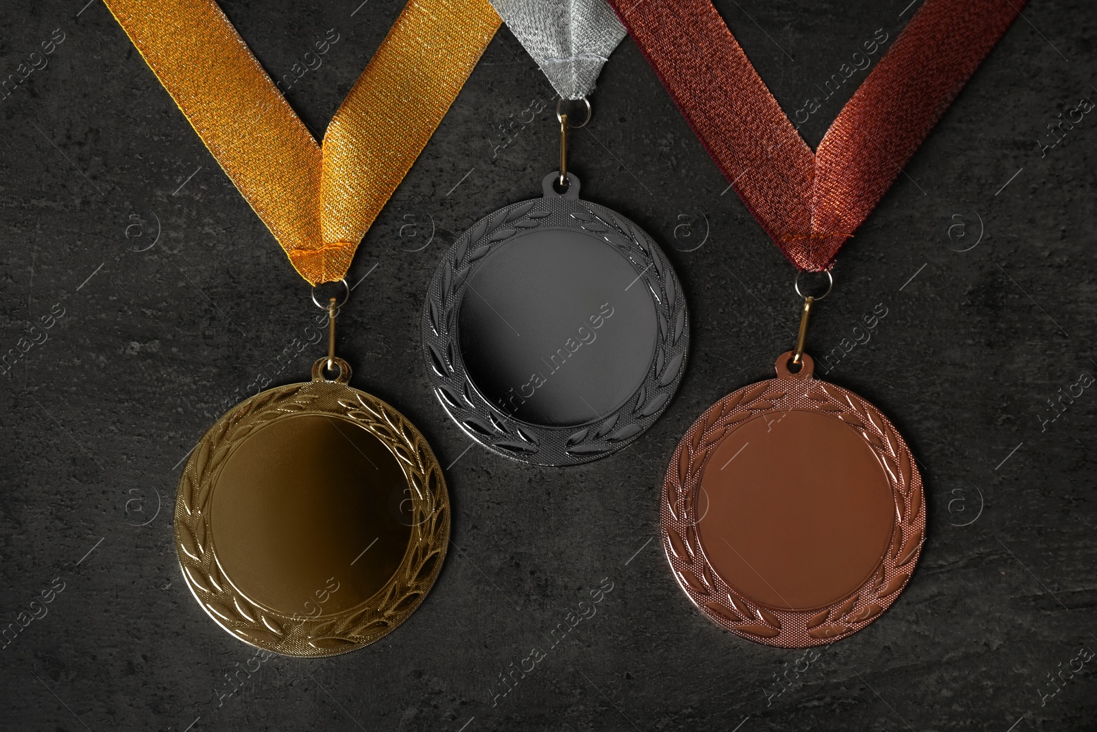 Photo of Gold, silver and bronze medals on grey stone background, flat lay. Space for design