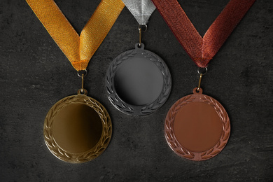 Gold, silver and bronze medals on grey stone background, flat lay. Space for design