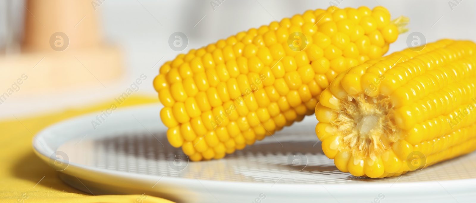 Image of Tasty corn cobs on plate, closeup. Banner design 