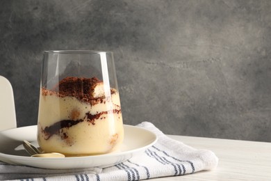 Photo of Delicious tiramisu in glass on white wooden table, closeup. Space for text