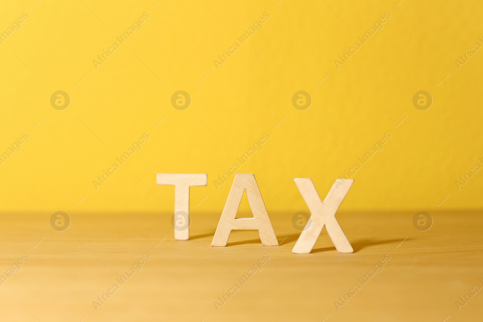 Photo of Word TAX on table against color background