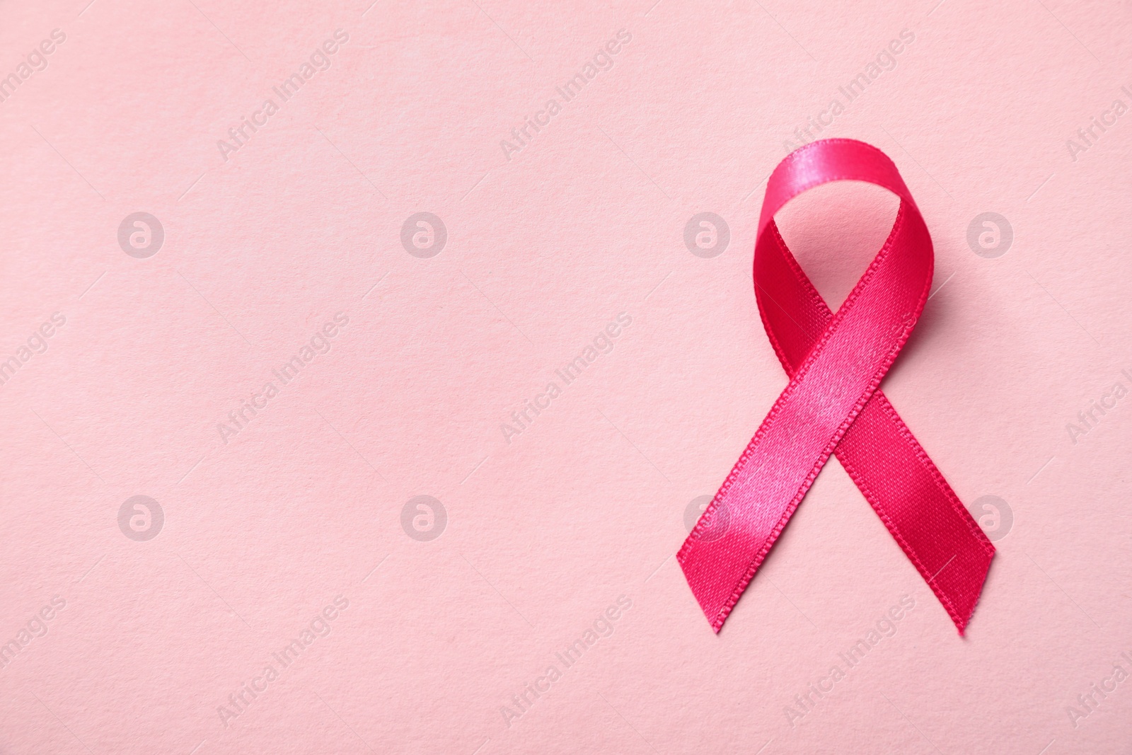 Photo of Pink ribbon on color background, top view with space for text. Breast cancer awareness concept