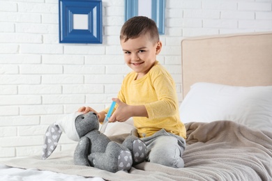 Photo of Cute child playing doctor with stuffed toy at hospital