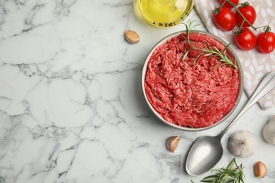 Photo of Fresh minced meat and other ingredients on white marble table, flat lay. Space for text
