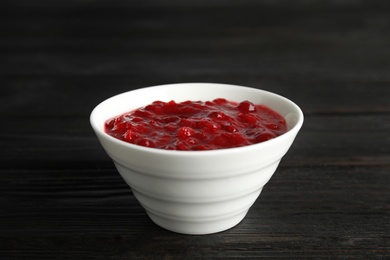 Bowl of cranberry sauce on wooden background, closeup