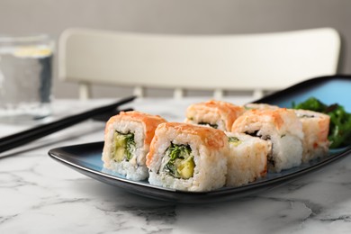 Photo of Delicious sushi rolls served on white marble table, closeup
