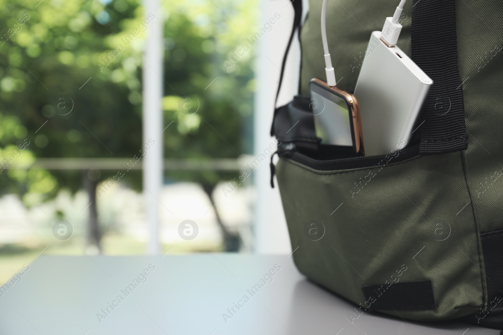 Photo of Smartphone charging with power bank in backpack on table, closeup. Space for text