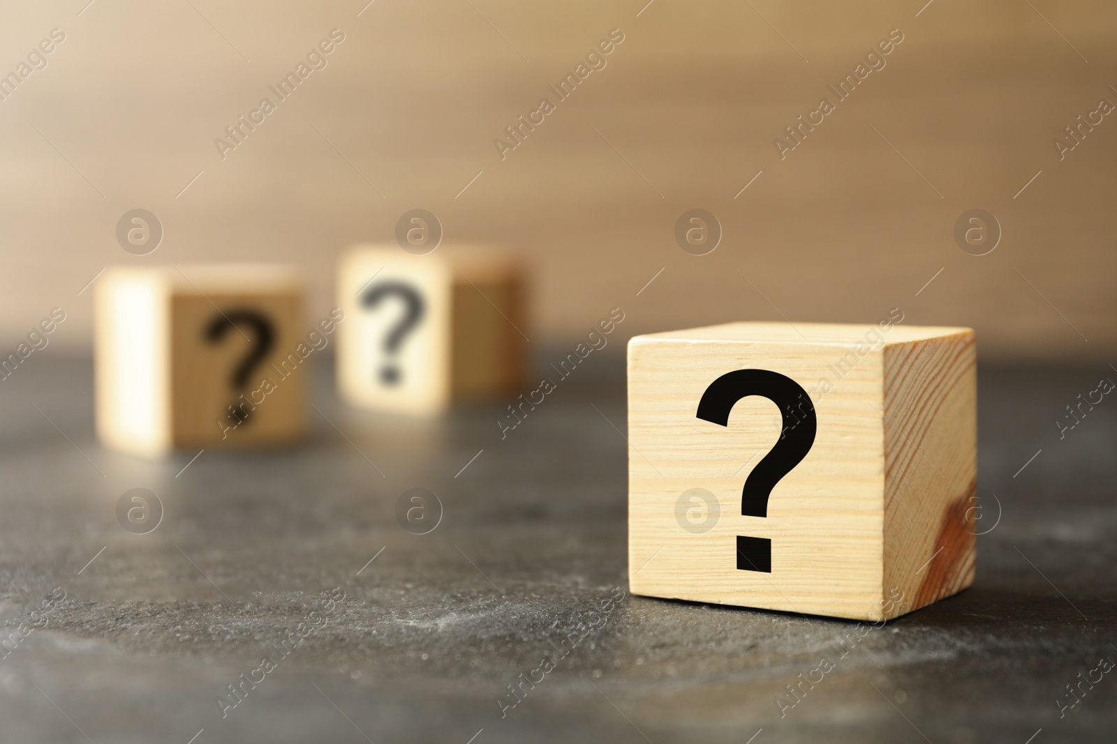 Photo of Cube with question mark on grey stone table, closeup. Space for text