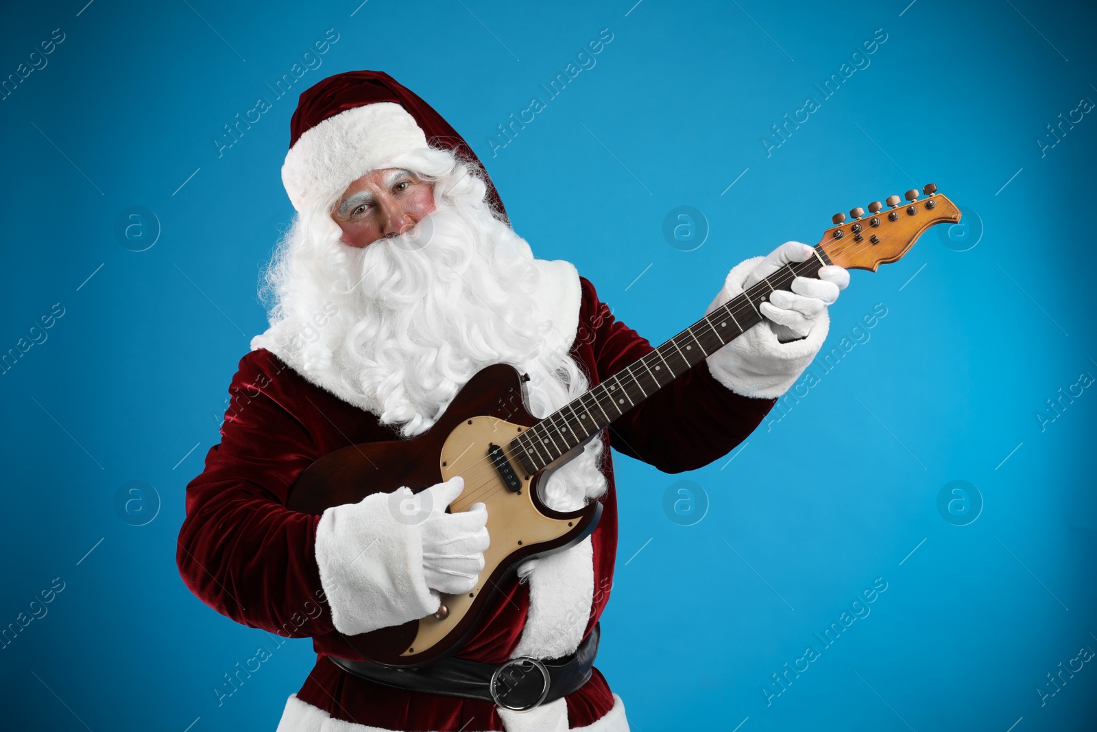 Photo of Santa Claus playing electric guitar on blue background. Christmas music