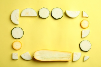 Fresh ripe cut zucchinis on yellow background, flat lay. Space for text