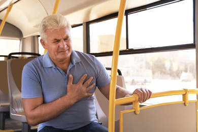 Image of Senior man having heart attack in public transport