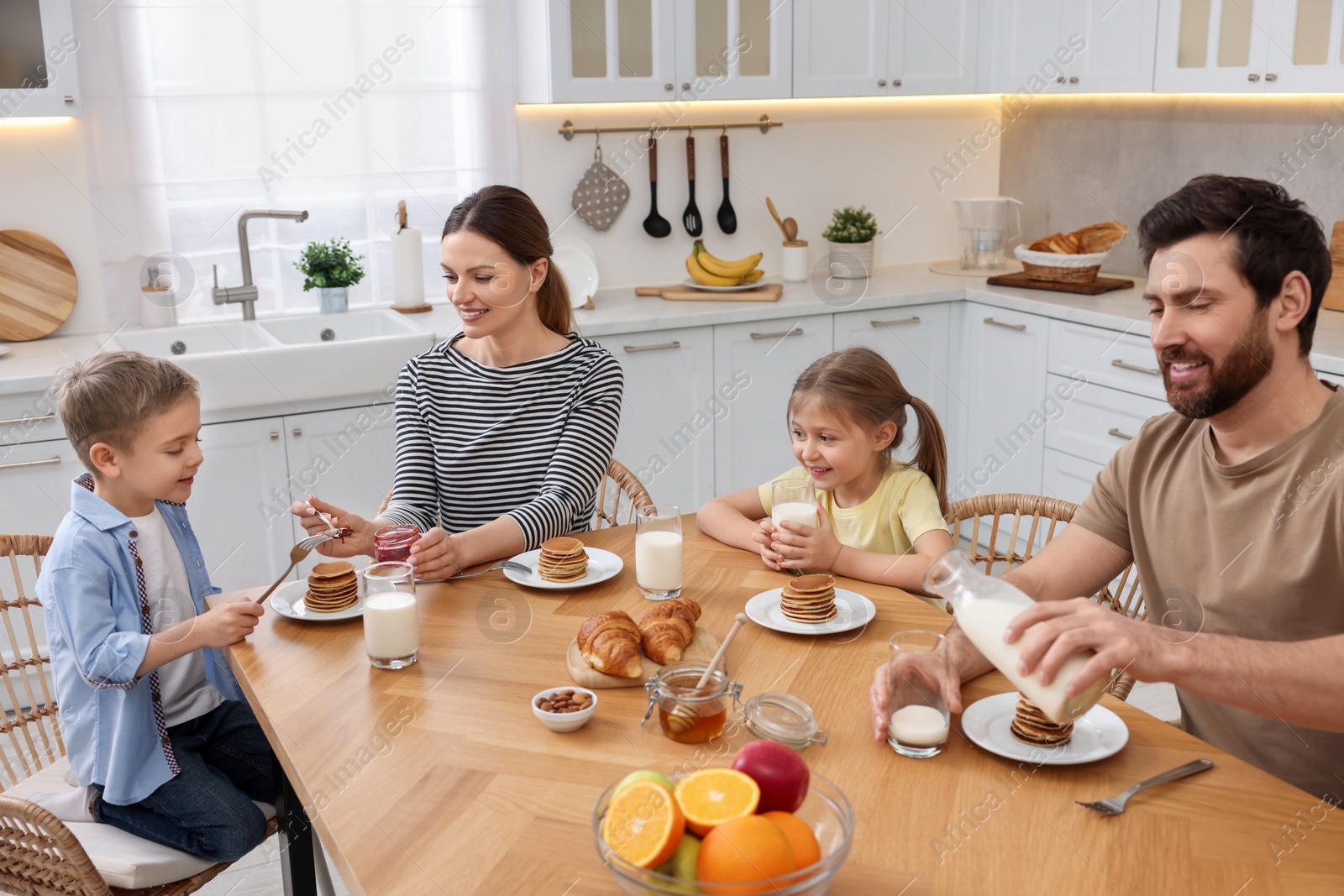 Photo of Happy family having breakfast at table in kitchen