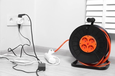 Photo of Extension cord reel plugged into socket indoors. Electrician's equipment