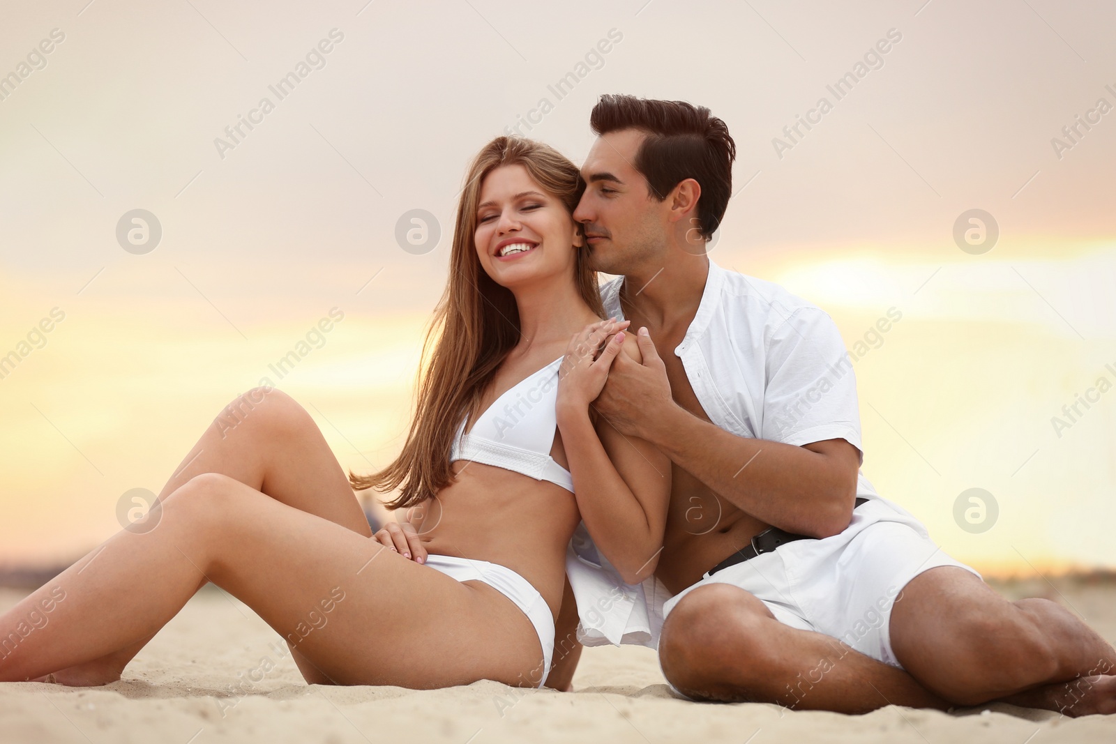 Photo of Happy young couple relaxing together on sea beach at sunset