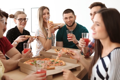 Young people having fun party with delicious pizza indoors