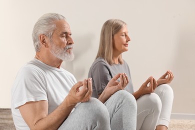 Photo of Senior couple practicing yoga at home, selective focus