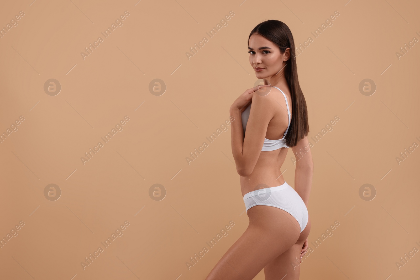 Photo of Young woman in stylish white bikini on beige background. Space for text