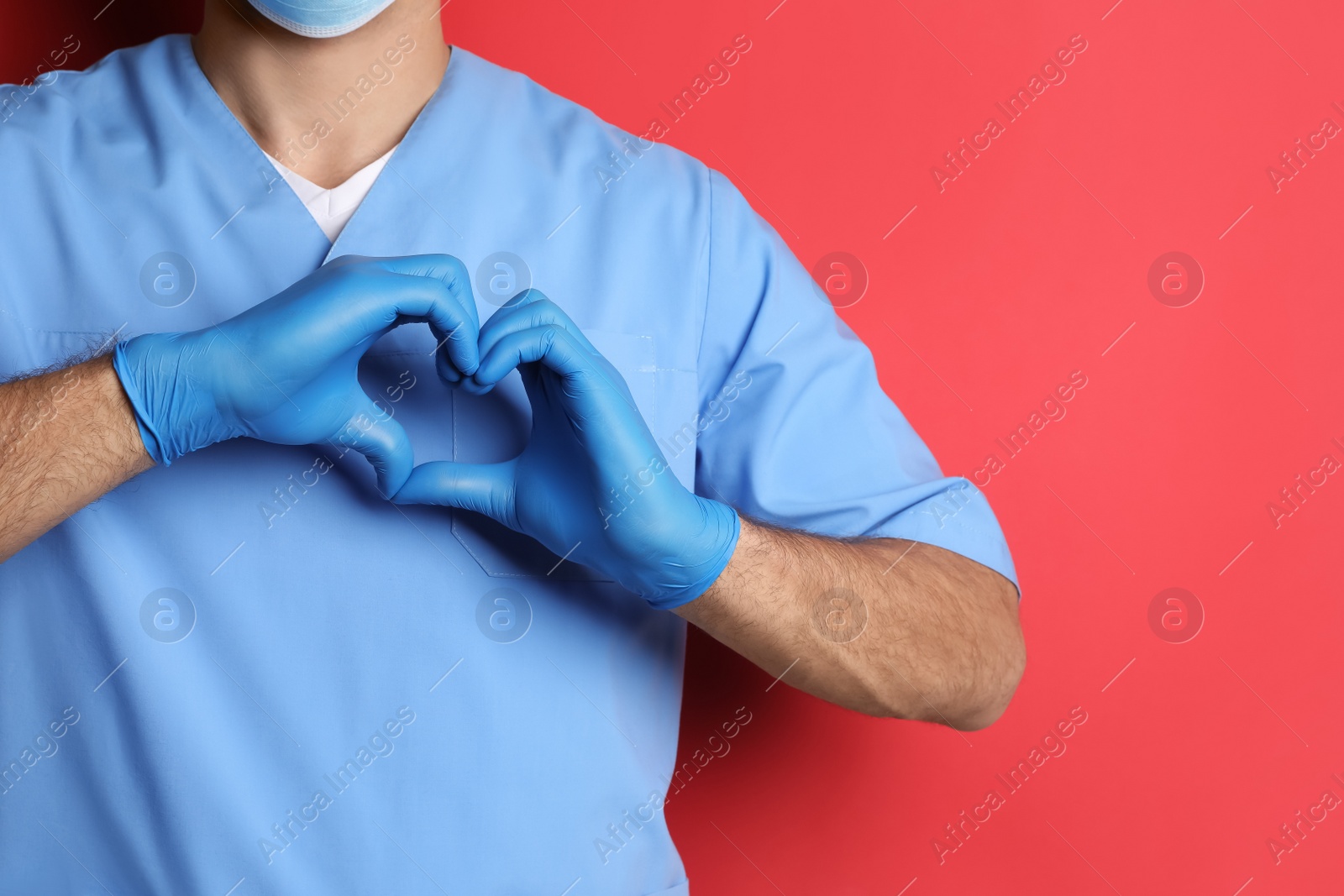 Photo of Doctor making heart with hands on red background, closeup. Space for text