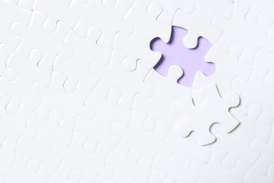Photo of Blank white puzzle with separated piece on violet background, top view. Space for text