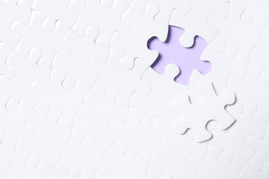 Blank white puzzle with separated piece on violet background, top view. Space for text