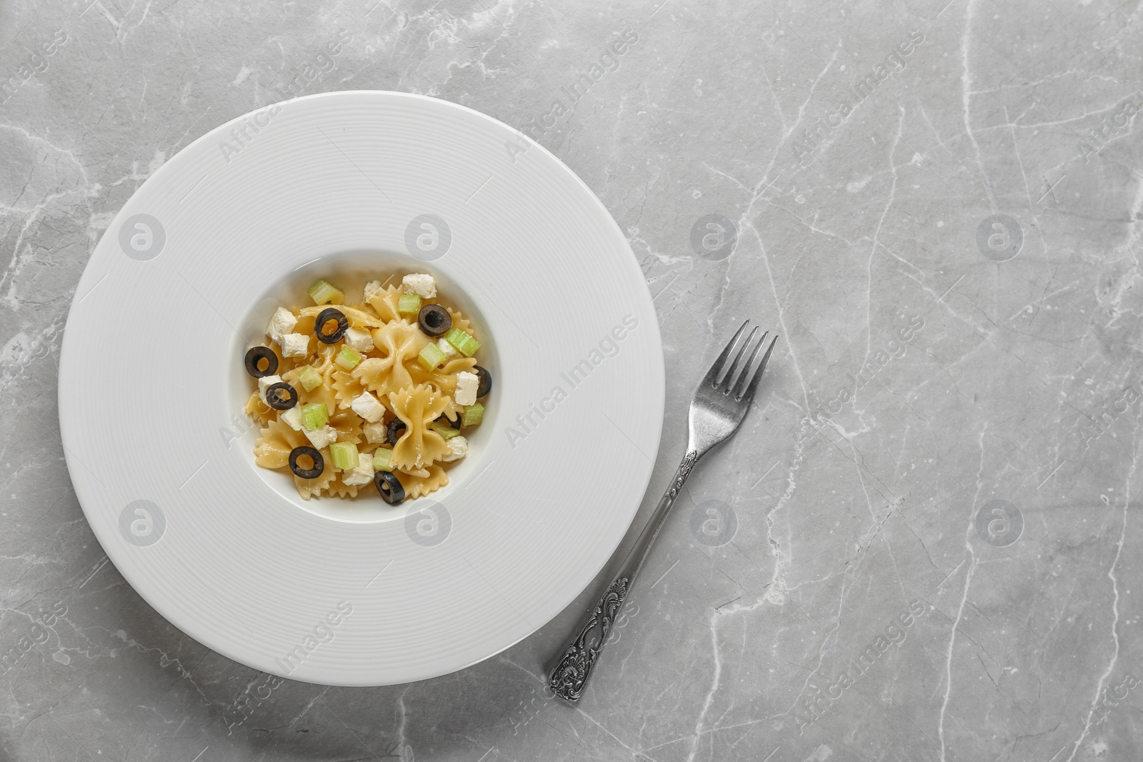 Photo of Tasty pasta salad with black olives and cheese on table