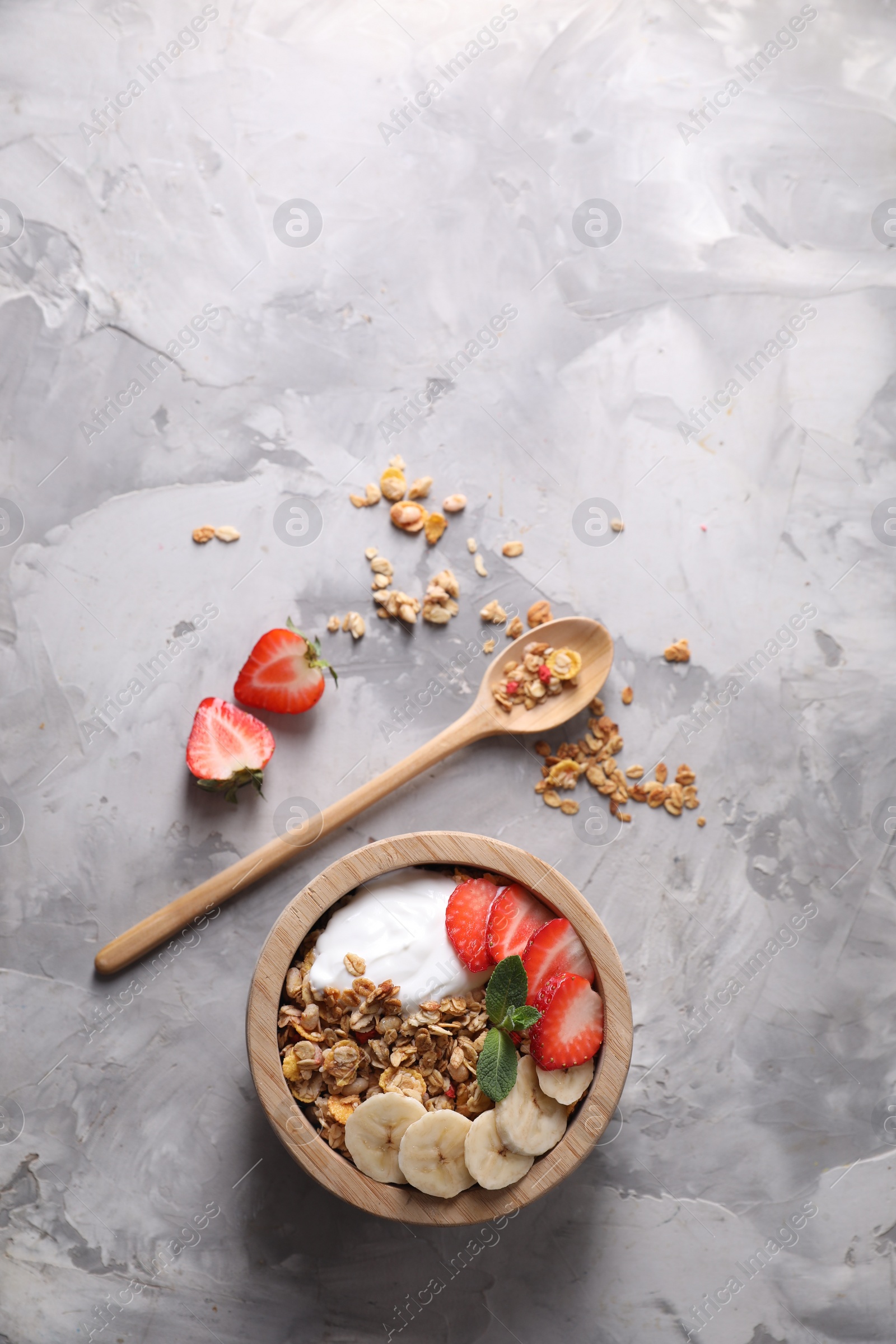 Photo of Tasty granola served on gray textured table, flat lay. Space for text