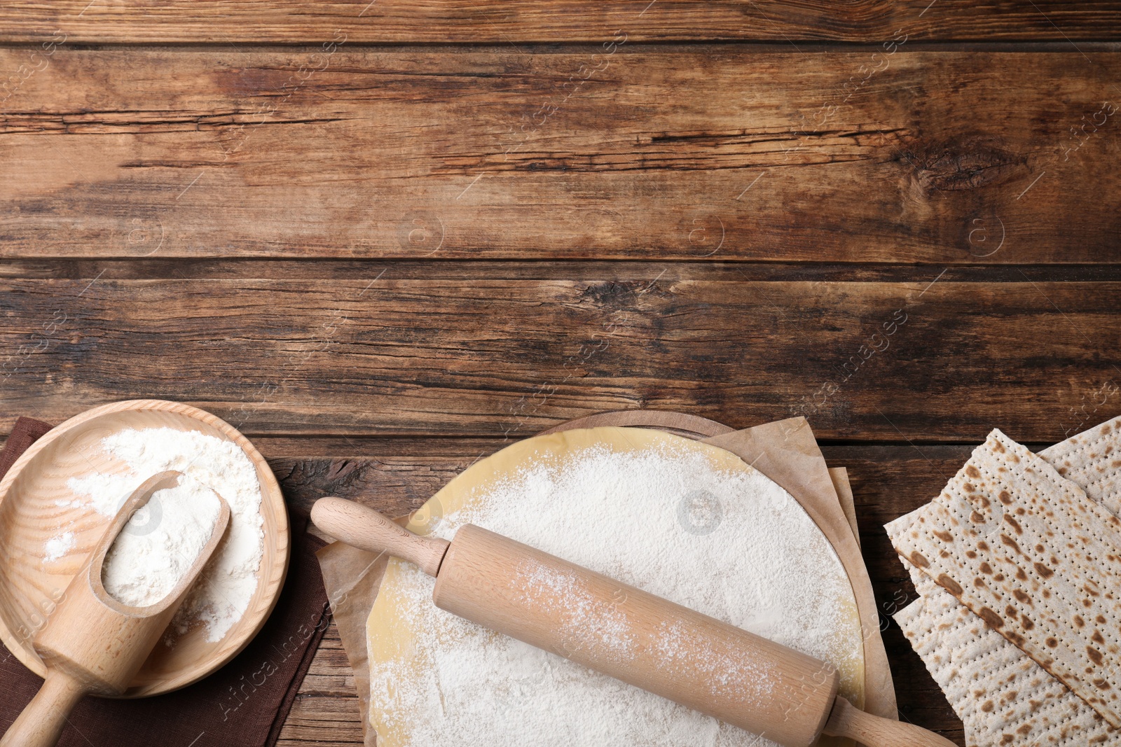 Photo of Matzos and raw dough on wooden table, flat lay. Space for text