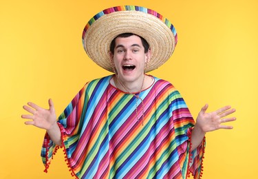 Photo of Excited man in Mexican sombrero hat and poncho on yellow background