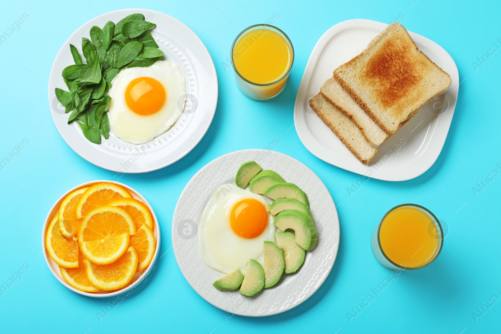 Photo of Flat lay composition with fried eggs on light blue background. Healthy breakfast