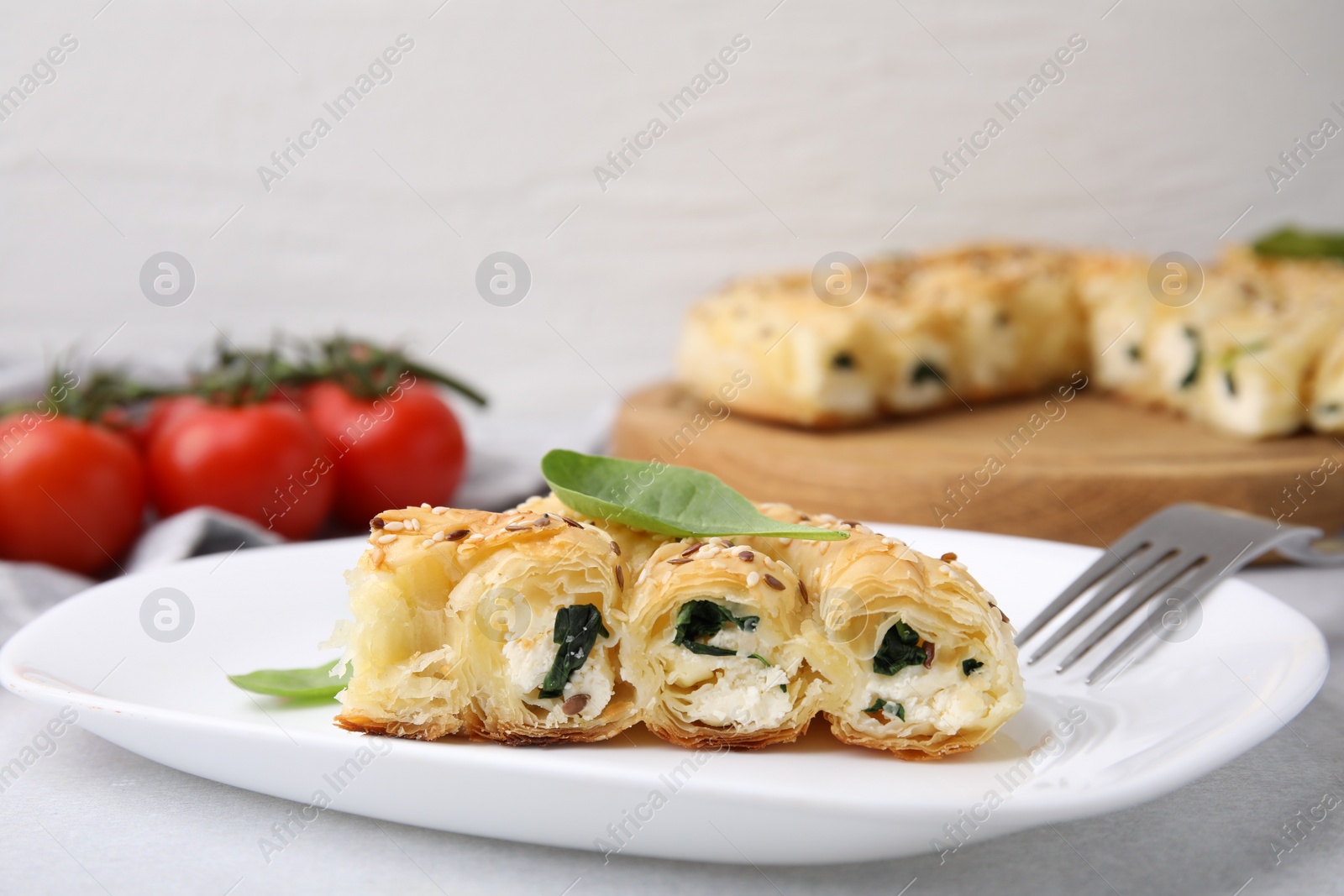 Photo of Piece of delicious puff pastry with spinach on light table, closeup