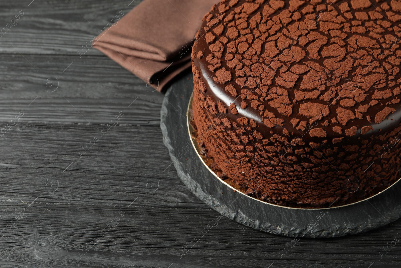 Photo of Delicious chocolate truffle cake on black wooden table, space for text