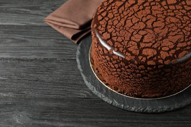 Photo of Delicious chocolate truffle cake on black wooden table, space for text