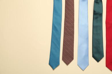 Different neckties on beige background, flat lay. Space for text