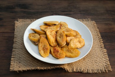 Photo of Tasty deep fried banana slices on wooden table