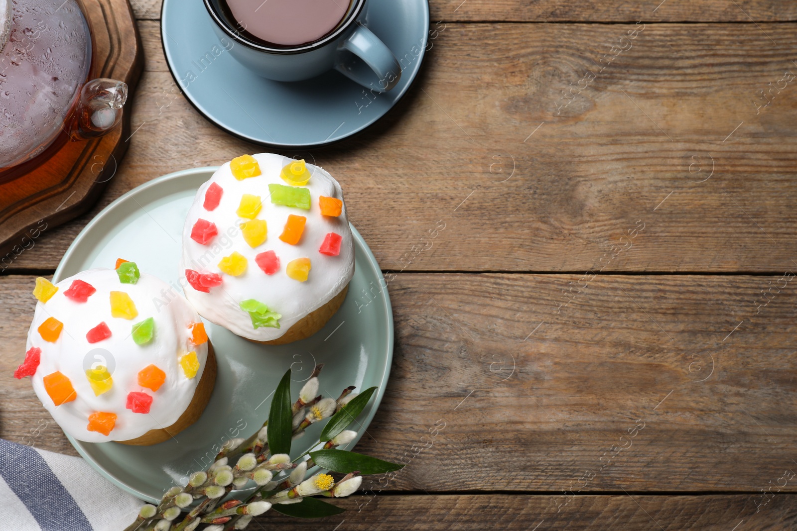 Photo of Beautiful Easter cakes and tea on wooden table, flat lay. Space for text