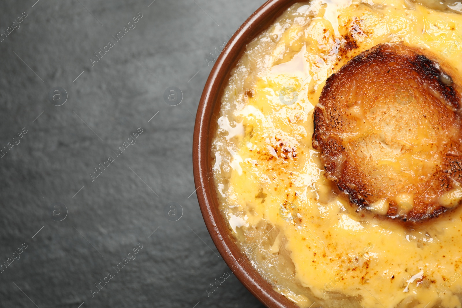 Photo of Tasty homemade french onion soup on black table, top view. Space for text