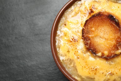 Tasty homemade french onion soup on black table, top view. Space for text