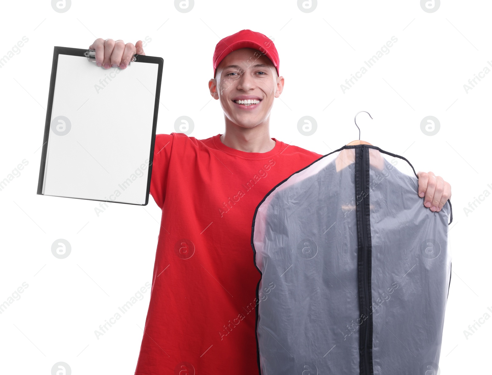 Photo of Dry-cleaning delivery. Happy courier holding garment cover with clothes and clipboard on white background