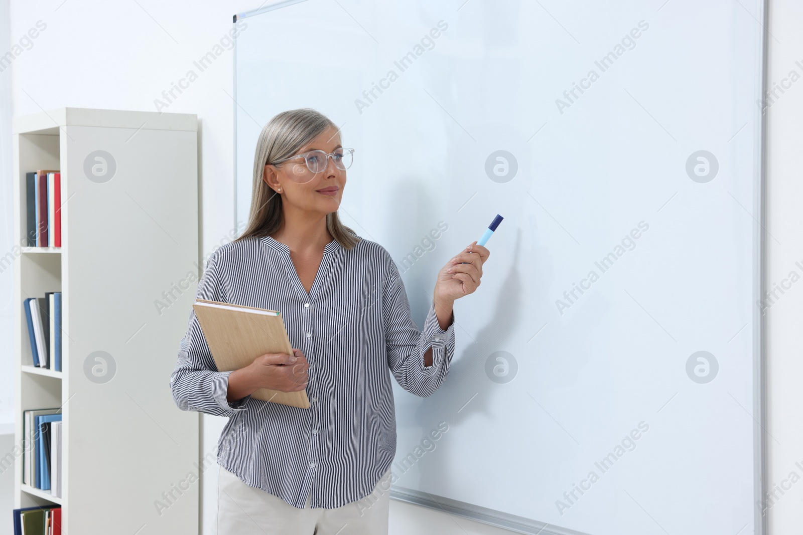 Photo of Professor giving lecture near whiteboard in classroom, space for text