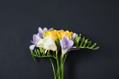 Photo of Beautiful fresh freesia flowers on black background, top view