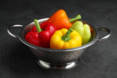 Photo of Colander with wet ripe bell peppers on grey table