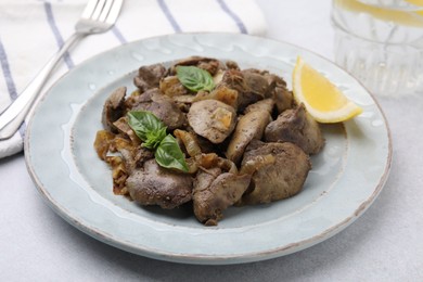 Photo of Delicious fried chicken liver with onion and basil on light table, closeup