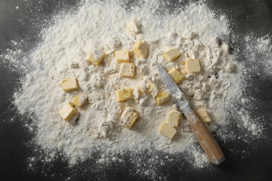 Photo of Making shortcrust pastry. Flour, butter and knife on grey table, top view