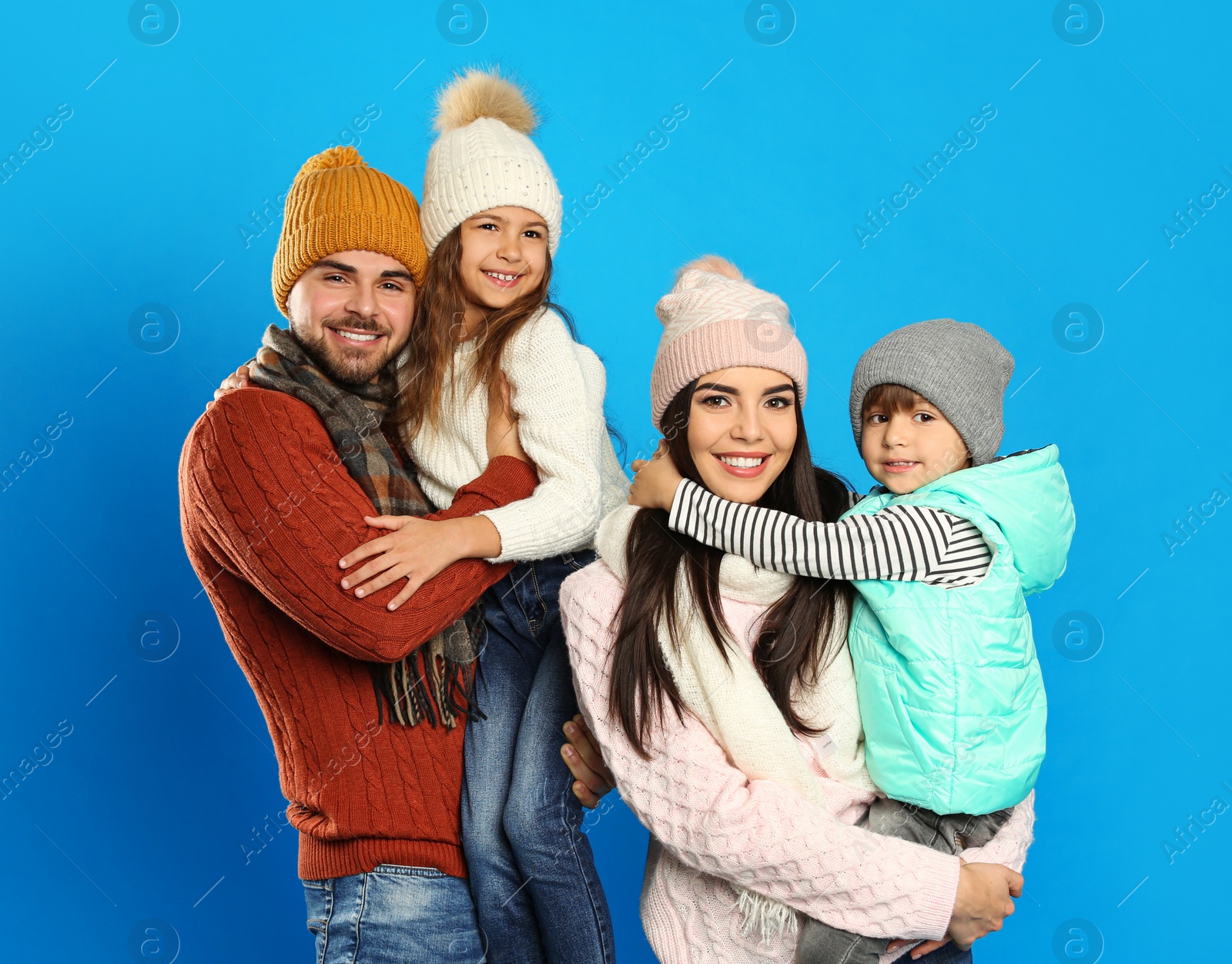 Photo of Happy family in warm clothes on blue background. Winter vacation