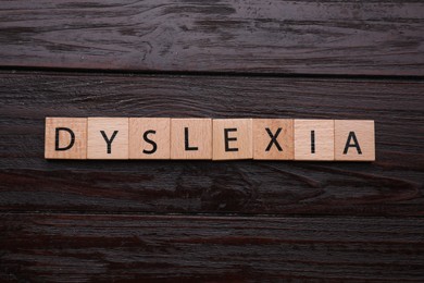 Photo of Cubes with word Dyslexia on wooden background, flat lay