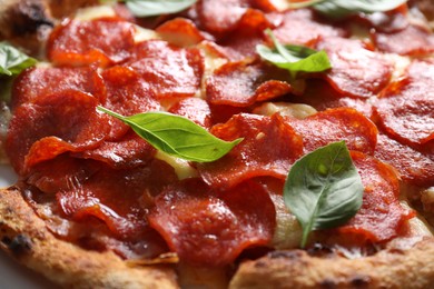 Tasty pepperoni pizza with basil on table, closeup