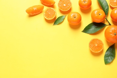 Fresh tangerines and leaves on color background, flat lay with space for text. Citrus fruits